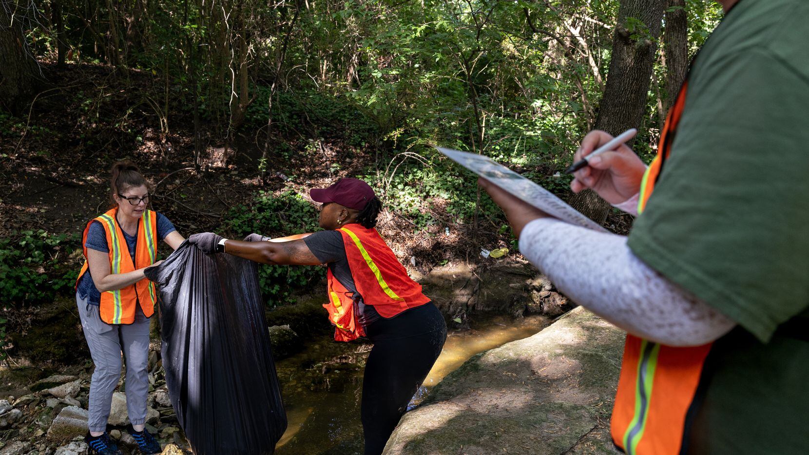 Volunteers Cynthia Smoot and Angelita Howard collect trash as Thelva Balkus counts the items...