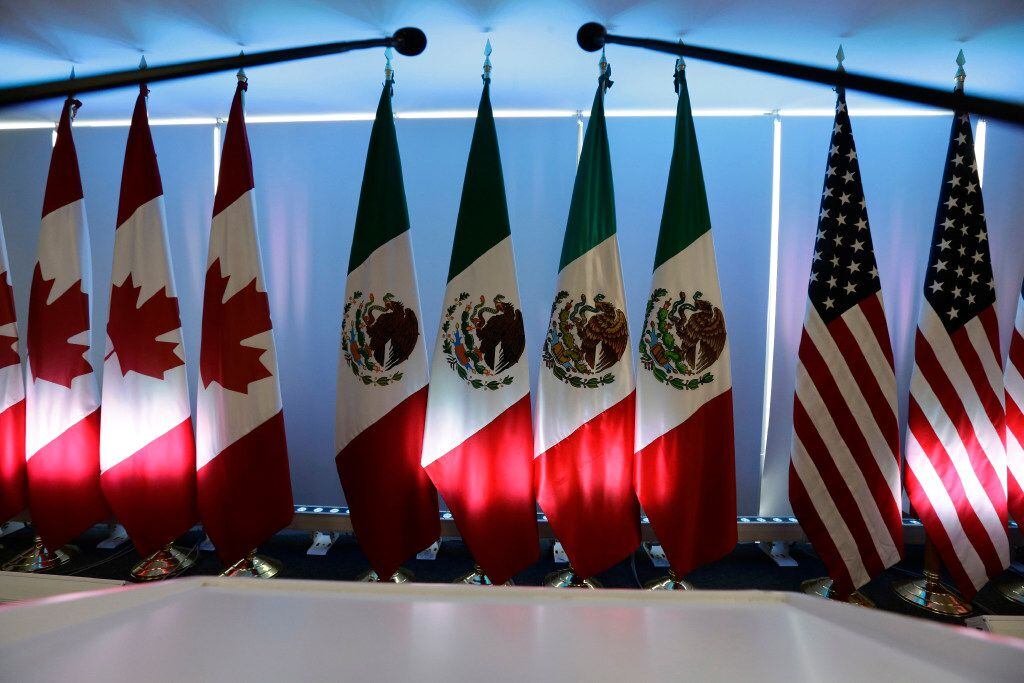 National flags representing Canada, Mexico, and the U.S. are lit by stage lights at the...