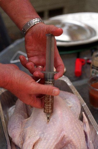 John Bass demonstrates injecting the turkey.