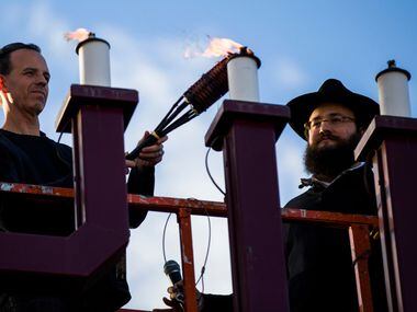 Evan Bundis, left, and Rabbi Moshe Naparstek, right, light large menorah at the Aaron Family...