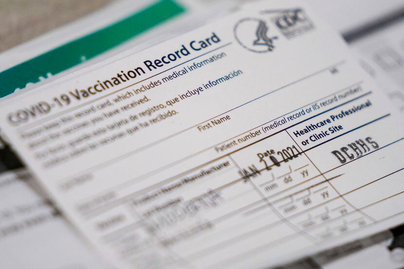 Vaccination record cards sit ready at a station at the Dallas County  COVID-19...
