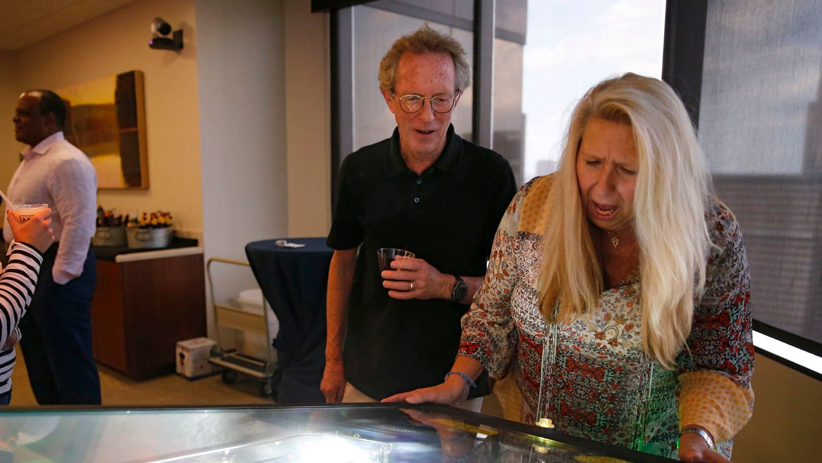 Sharon Blackstock plays a game of pinball while Rick Addison watches her lose the ball...