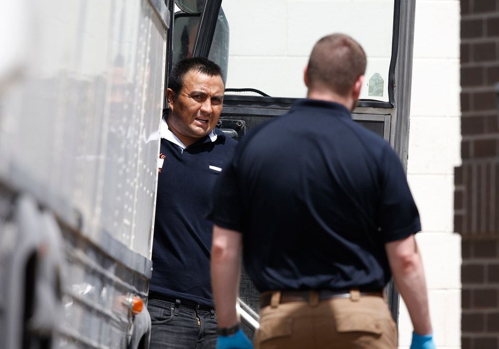 Detained immigrants unload from buses at the federal courthouse in McAllen, Texas, on June...