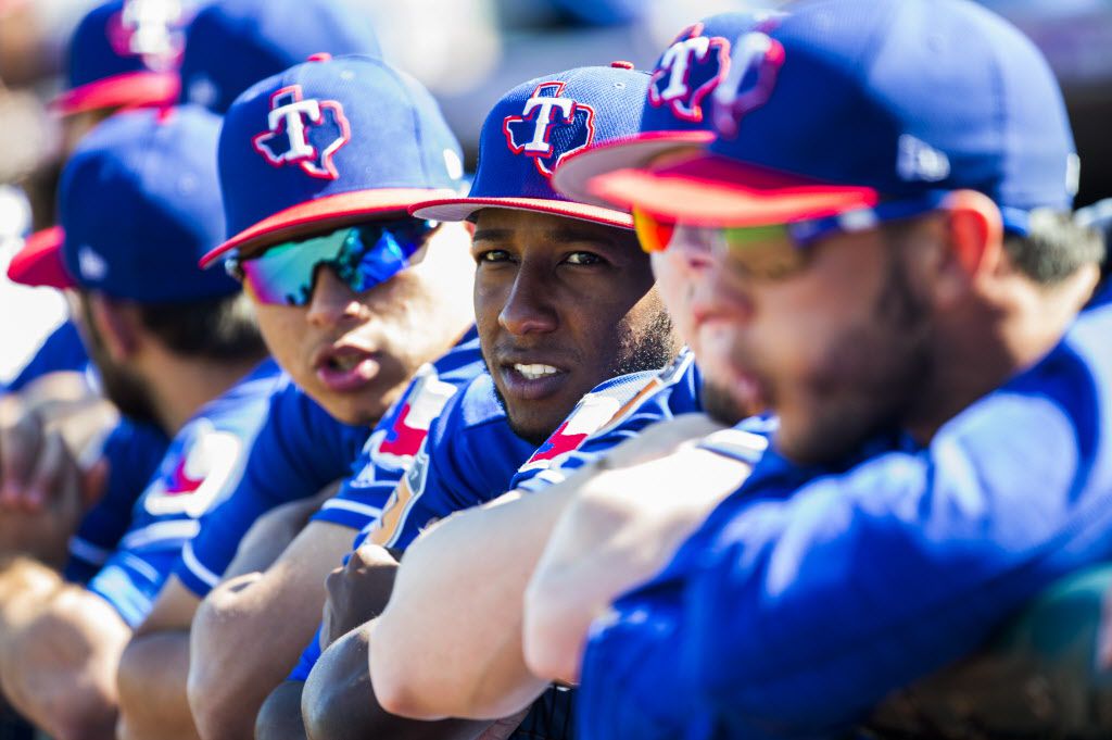 Texas Rangers third baseman Jurickson Profar (19, center) hangs out on the dugout fence with...