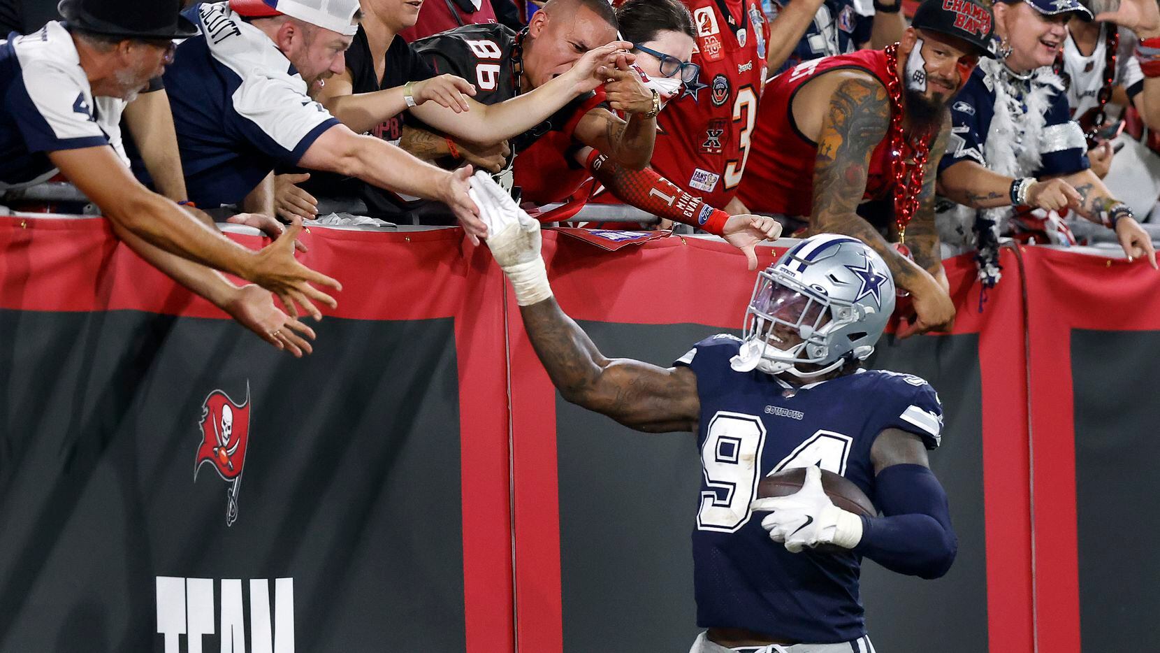 Dallas Cowboys defensive end Randy Gregory (94) receives high-fives from fans after his second quarter fumble recovery against the Tampa Bay Buccaneers at Raymond James Stadium in Tampa, Florida, Thursday, September 9, 2021. The Cowboys faced the Tampa Bay Buccaneers in the NFL season opener.