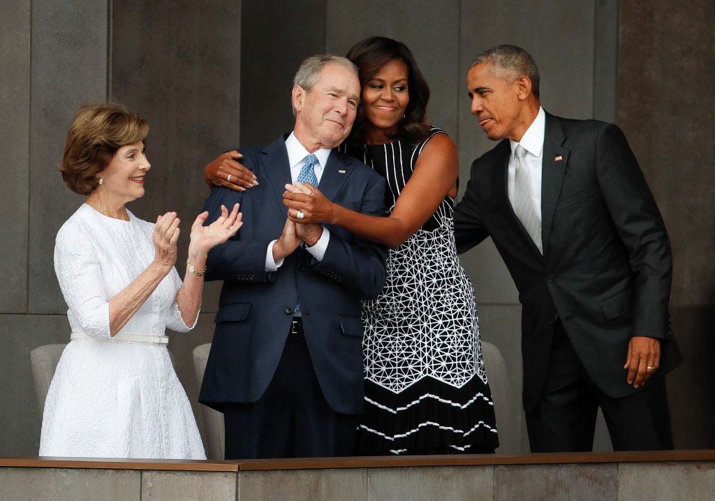 First lady Michelle Obama (center) hugs former President George W. Bush, as President Barack...