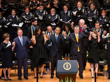 President Barack Obama joins hands with Dallas Mayor Mike Rawlings and other dignitaries...