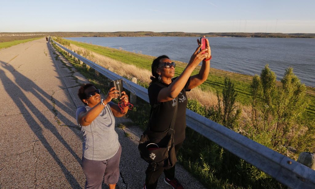 Amina Duncan and Victouria (cq) Lecoq take photos of the setting sun from the dam at Joe...