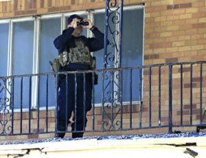  A police officer uses binoculars across from the Muhammad Mosque to monitor the situation....
