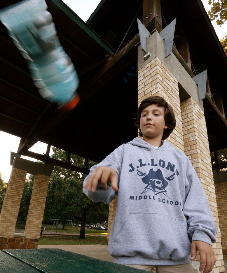 Ian Interrante, 12, demonstrates the flipping bottles game at Lindsley Park in Dallas.