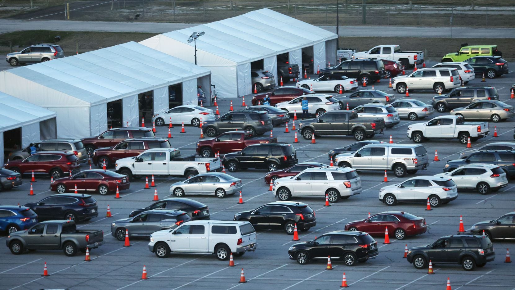 Vehicles line up at the drive-through COVID-19 vaccination clinic at Texas Motor Speedway in...