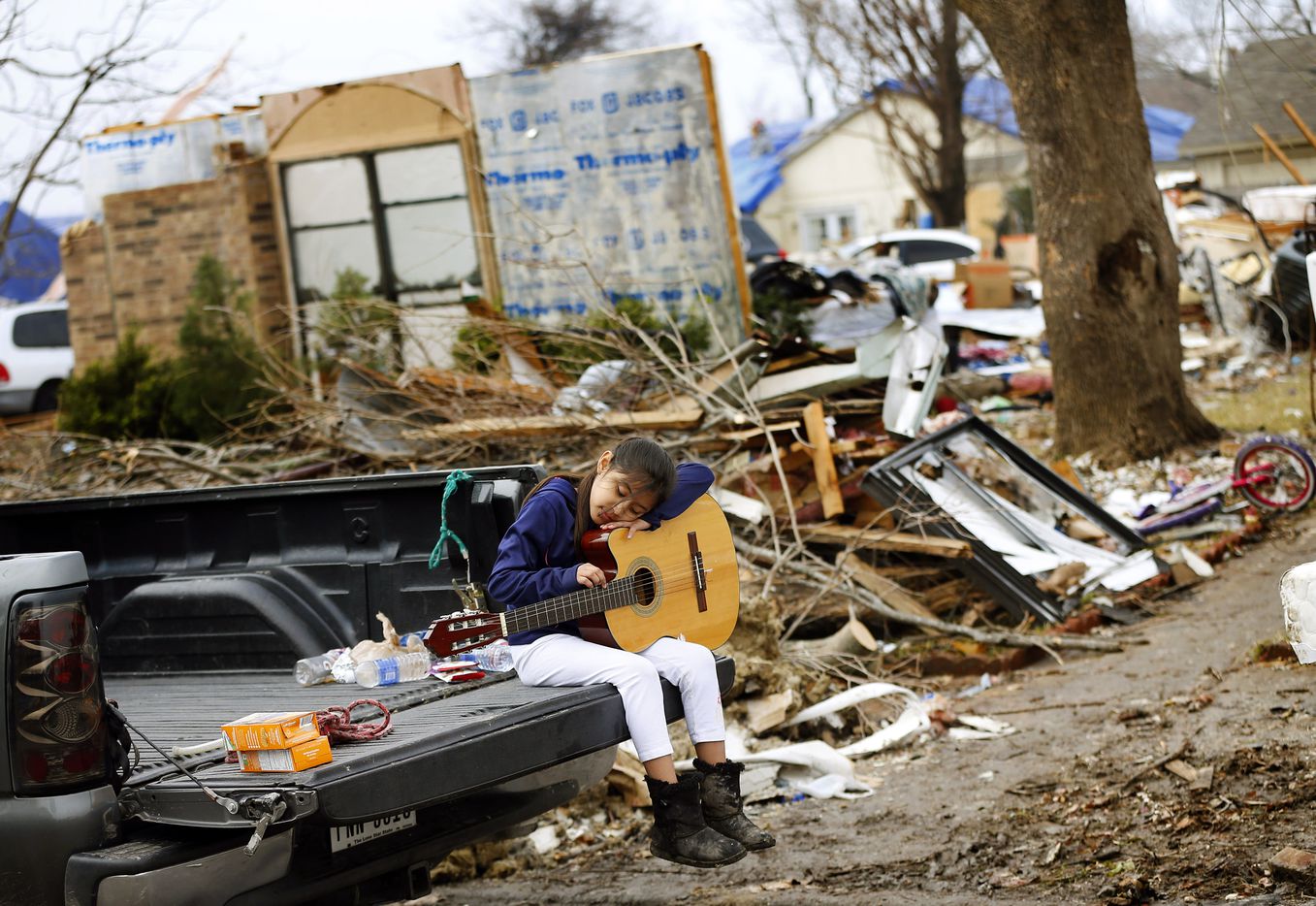 Natalie Rojas, 8, strums a guitar found in the bedroom of her tornado damaged home on...