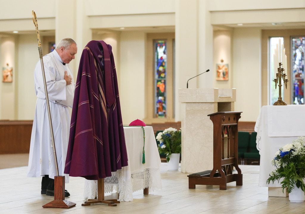 Bishop Edward J. Burns removes his miter, crozier, episcopal ring, pectoral cross and...