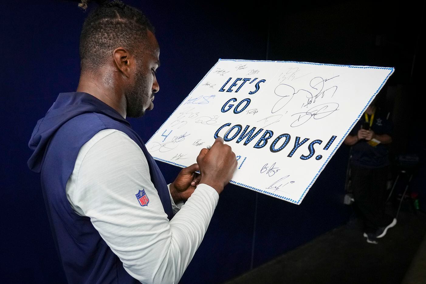 Dallas Cowboys defensive end Tarell Basham autographs a fans’ poster before an NFL preseason...