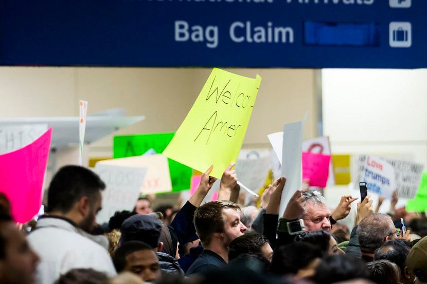 Manifestantes en la terminal internacional  del aeropuerto DFW muestran su desapruebo a la...