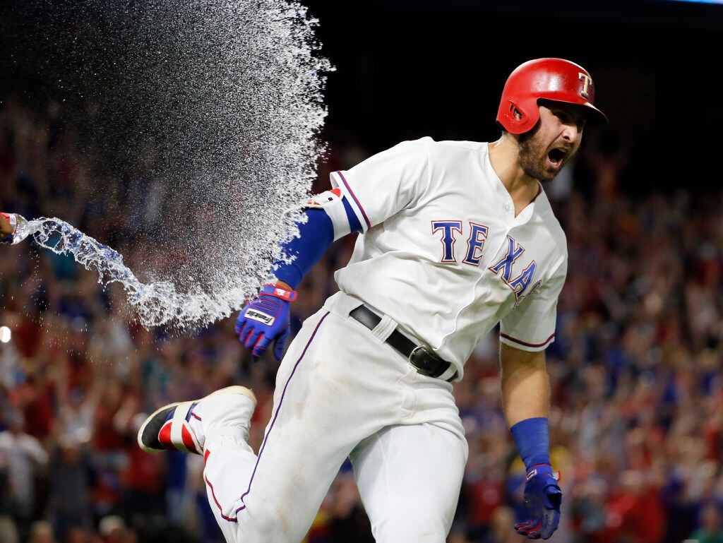 Texas Rangers' Keone Kela, out of photo at left, sprays a bottle of water over Joey Gallo as...