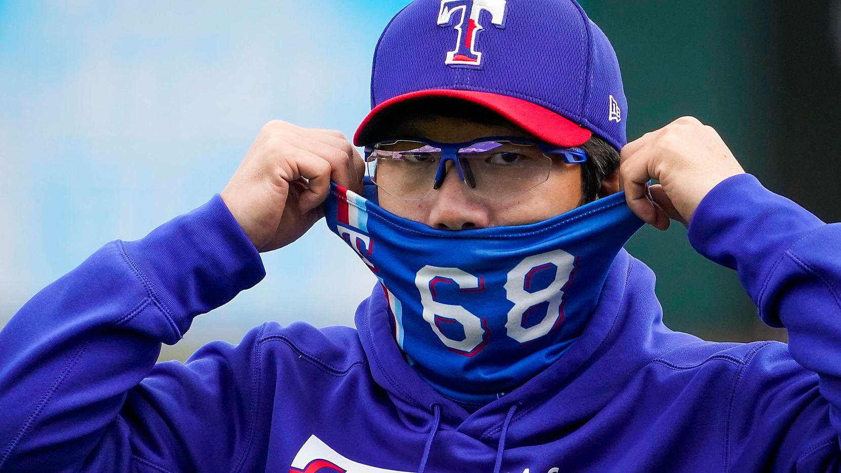 Texas Rangers pitcher Hyeon-jong Yang adjusts his face covering before of a spring training...