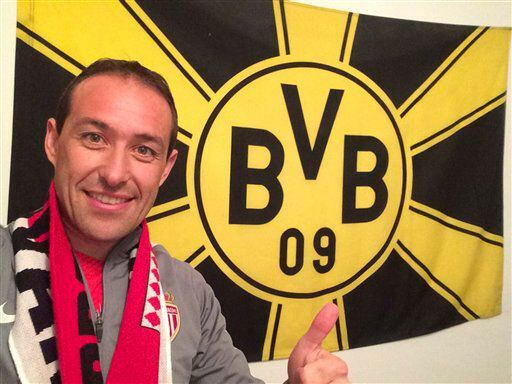 Un hincha del Mónaco levanta el pulgar frente a una bandera de Borussia Dortmund el...