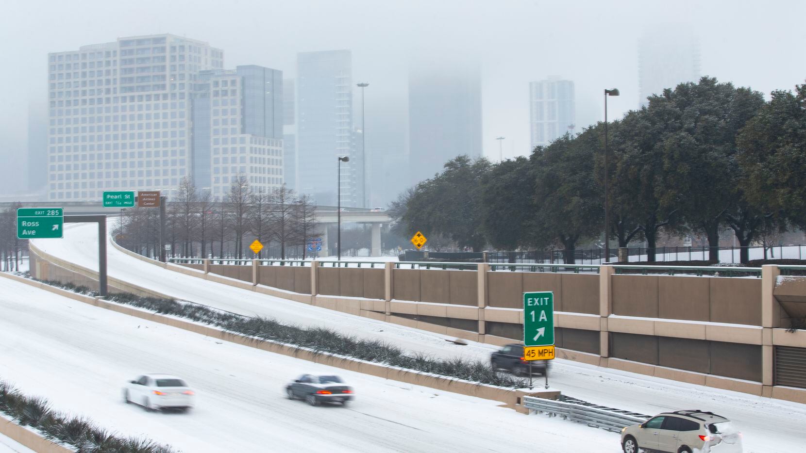 A foggy downtown and stalled car seen on a snowy and icy North Central Expressway in Dallas...