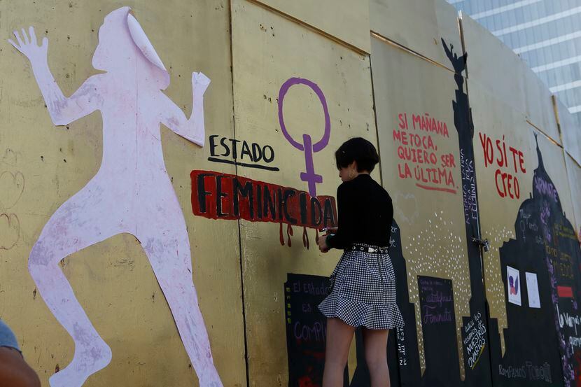 Una mujer termina una pinta en las paredes provisionales que se instalaron para proteger el...