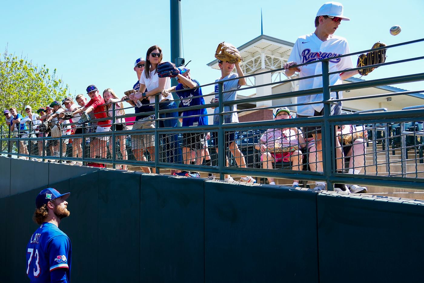 Texas Rangers pitcher Jake Latz tosses a ball to a fan before a spring training game against...