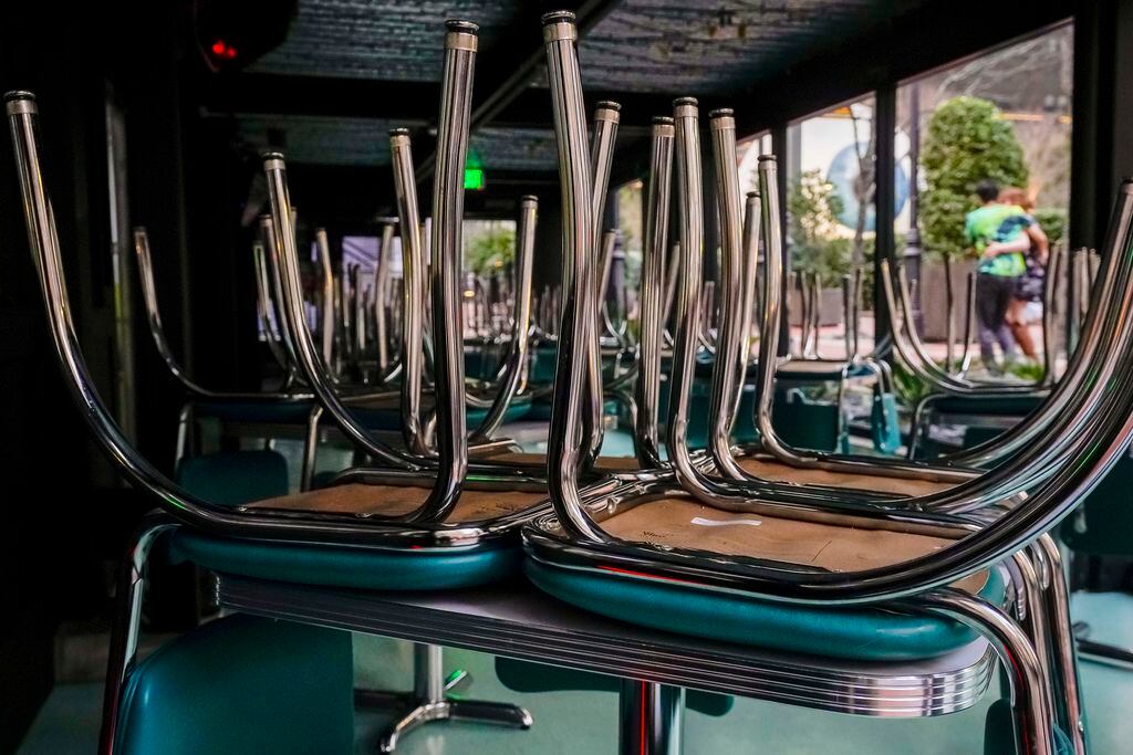 Chairs are stacked on tables at Queso Beso in downtown Dallas on March 16, 2020, after the...