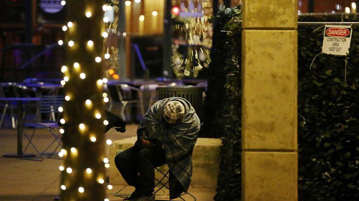 A homeless person slumped over in a chair in Pegasus Plaza in downtown Dallas on Dec. 31,...