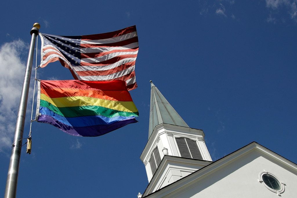 A gay pride rainbow flag flies along with the U.S. flag in front of the Asbury United...