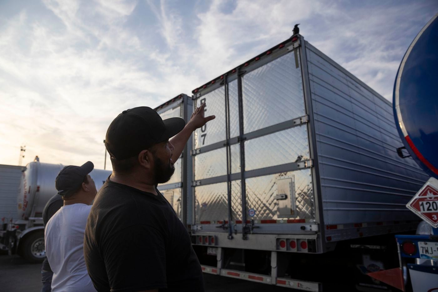 Truck driver Ignacio Arceo points to a bird as he jokes about the government sending it to...