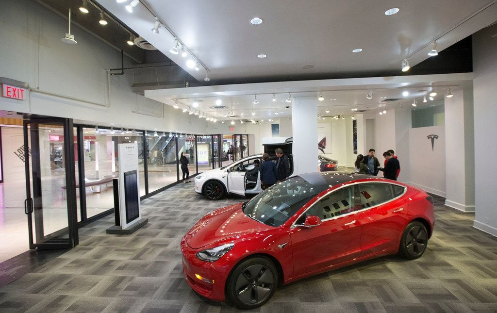 Shoppers speak with Tesla representatives while others explore the electric vehicles inside...