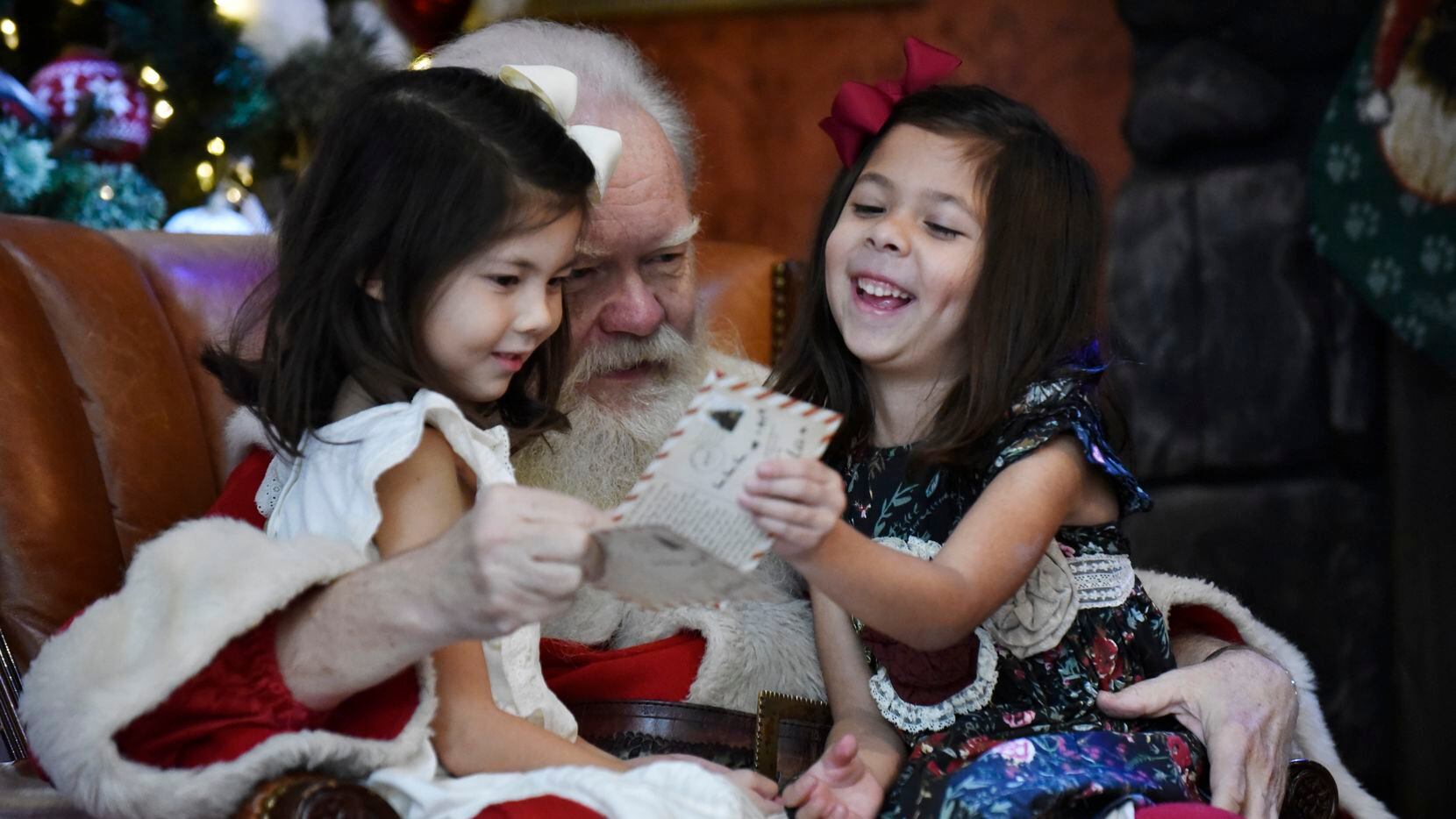 Santa Claus (Carl Anderson) is shown with Reece Carrasco, 6, left, and Reagan Carrasco, 6,...