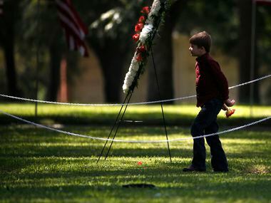 Magnus Ahrens, 8, son of fallen Dallas police officer Lorne Ahrens, walks a single flower to...