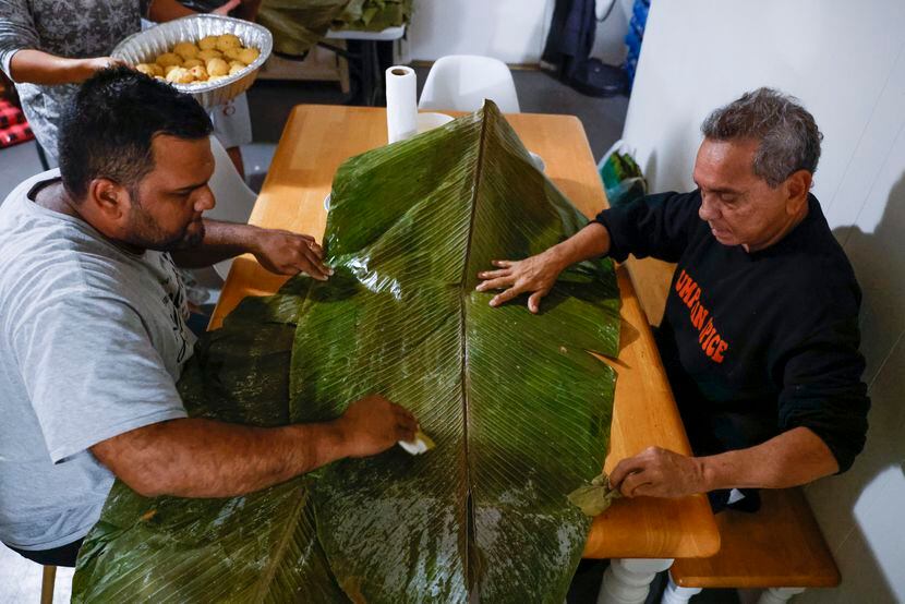 Luis Chacín, a la derecha y su hijo Harry Chacin limpian hojas de plátano mientras la...