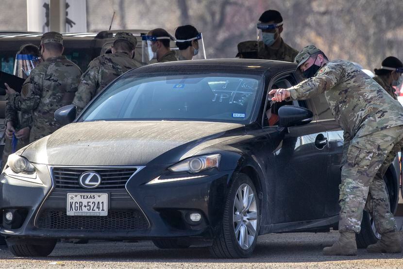 U.S. Army soldiers directed cars Wednesday at a FEMA vaccination site set up at Dallas' Fair...