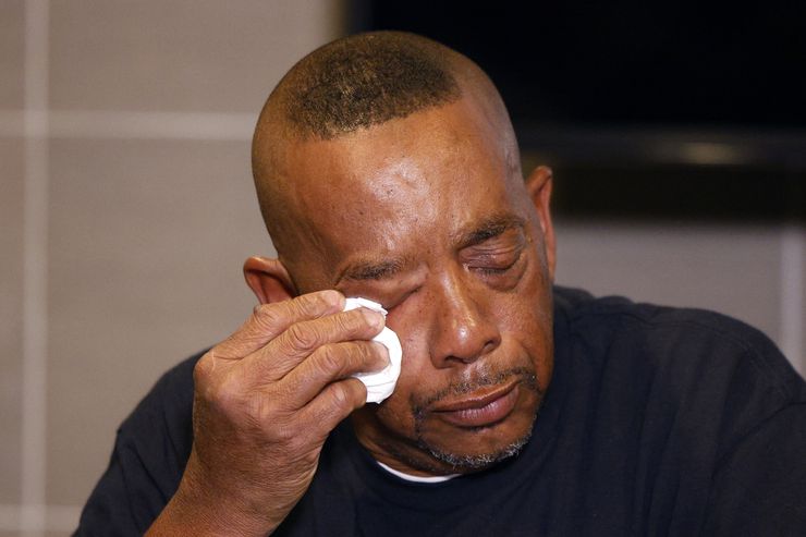 Kenneth Price, father of Kenneth Knotts, wipes away tears as he speaks during a news...