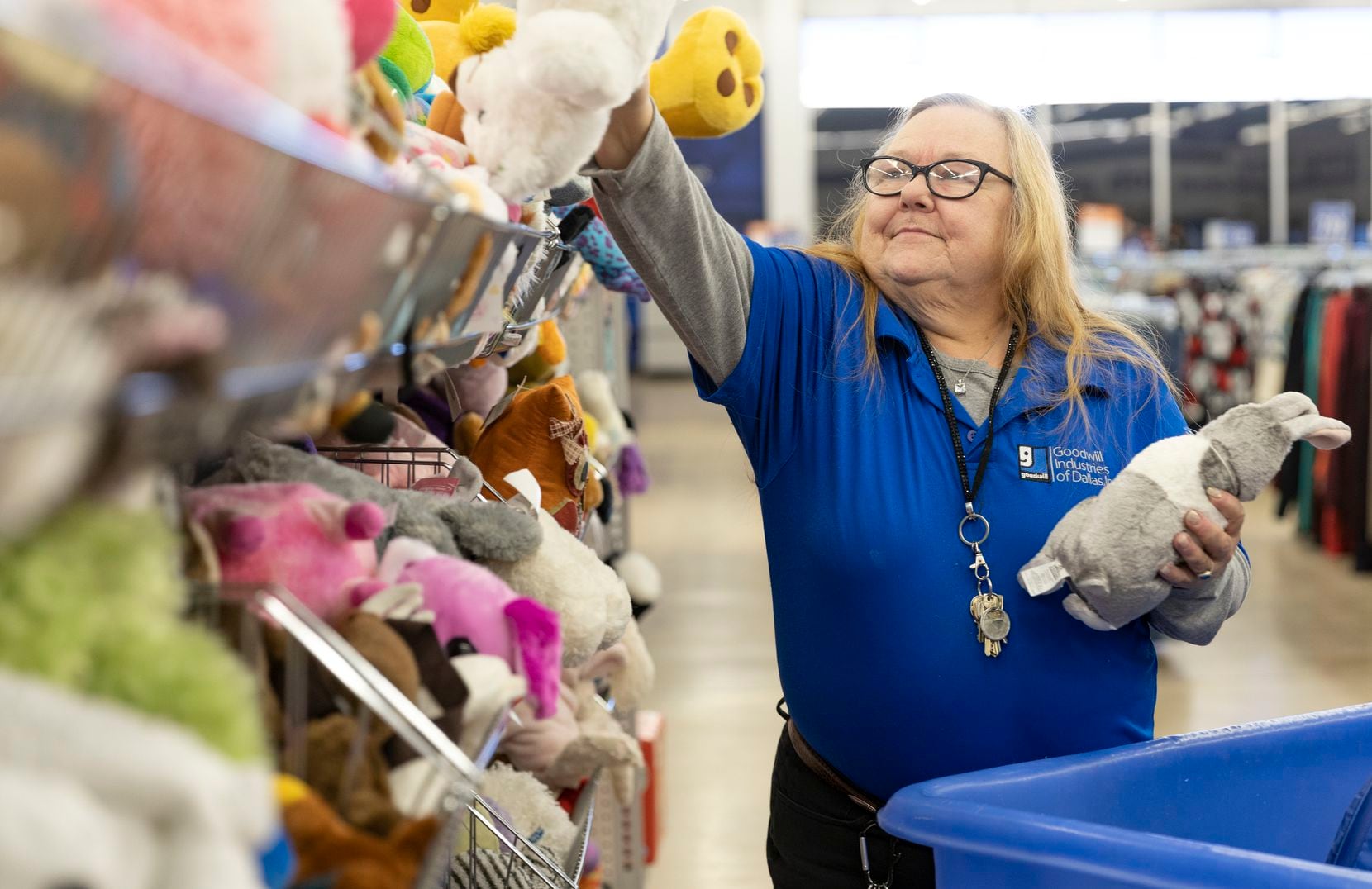 Goodwill employee Darla Rawls places a stuffed bear on the shelf as she restocks the store...