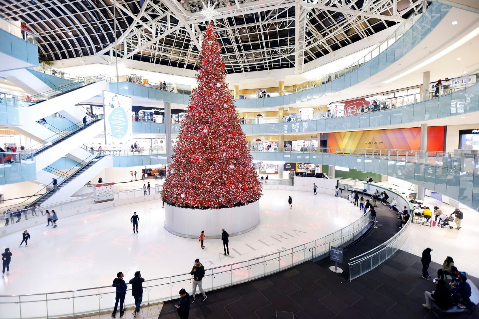 Skaters circle the 95-foot-high Christmas tree in the middle of Galleria Dallas' indoor ice...