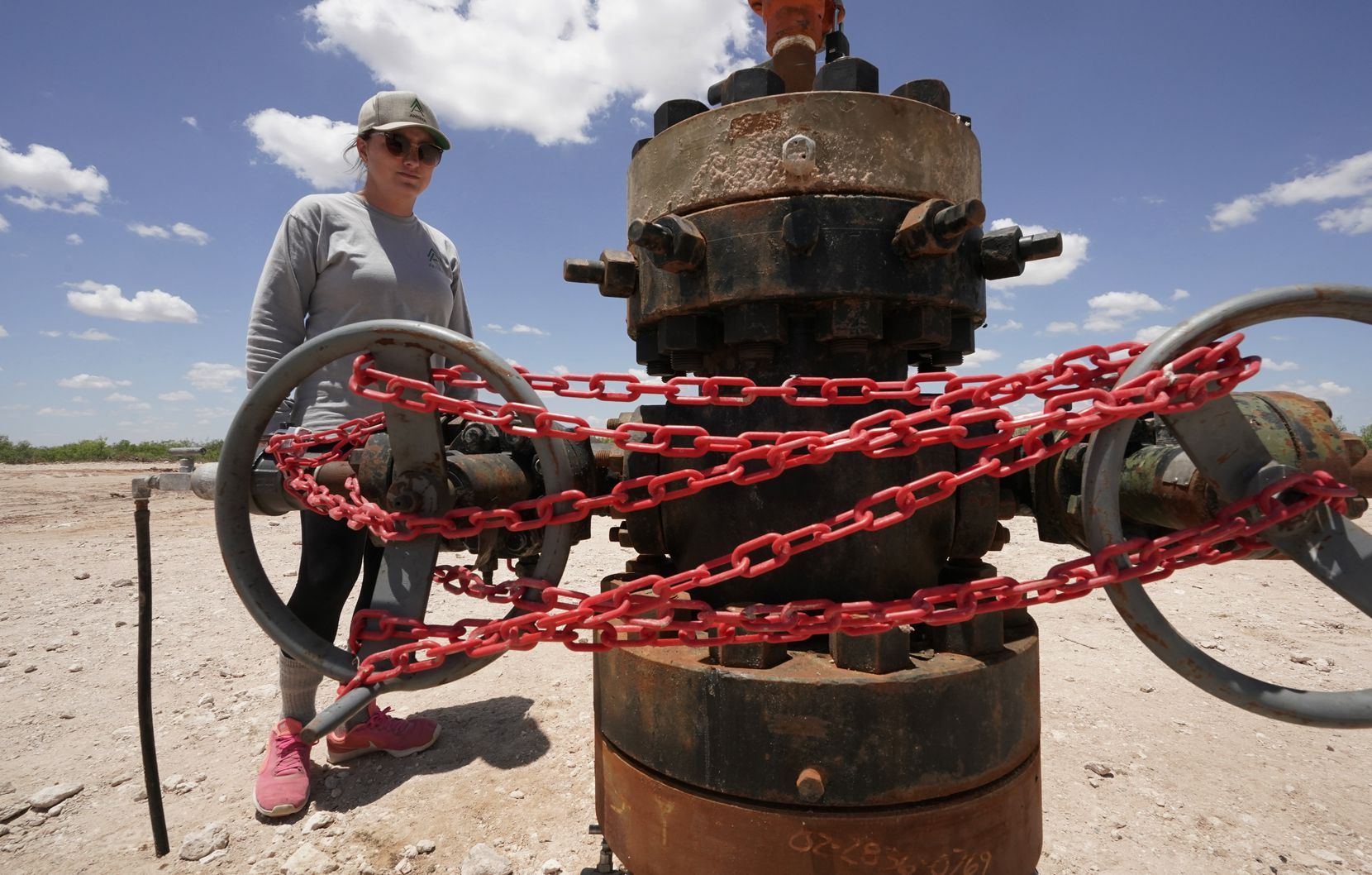 Ashley Williams Watt looks at an abandoned well wrapped with locks and chains on her ranch in Crane on July 9.