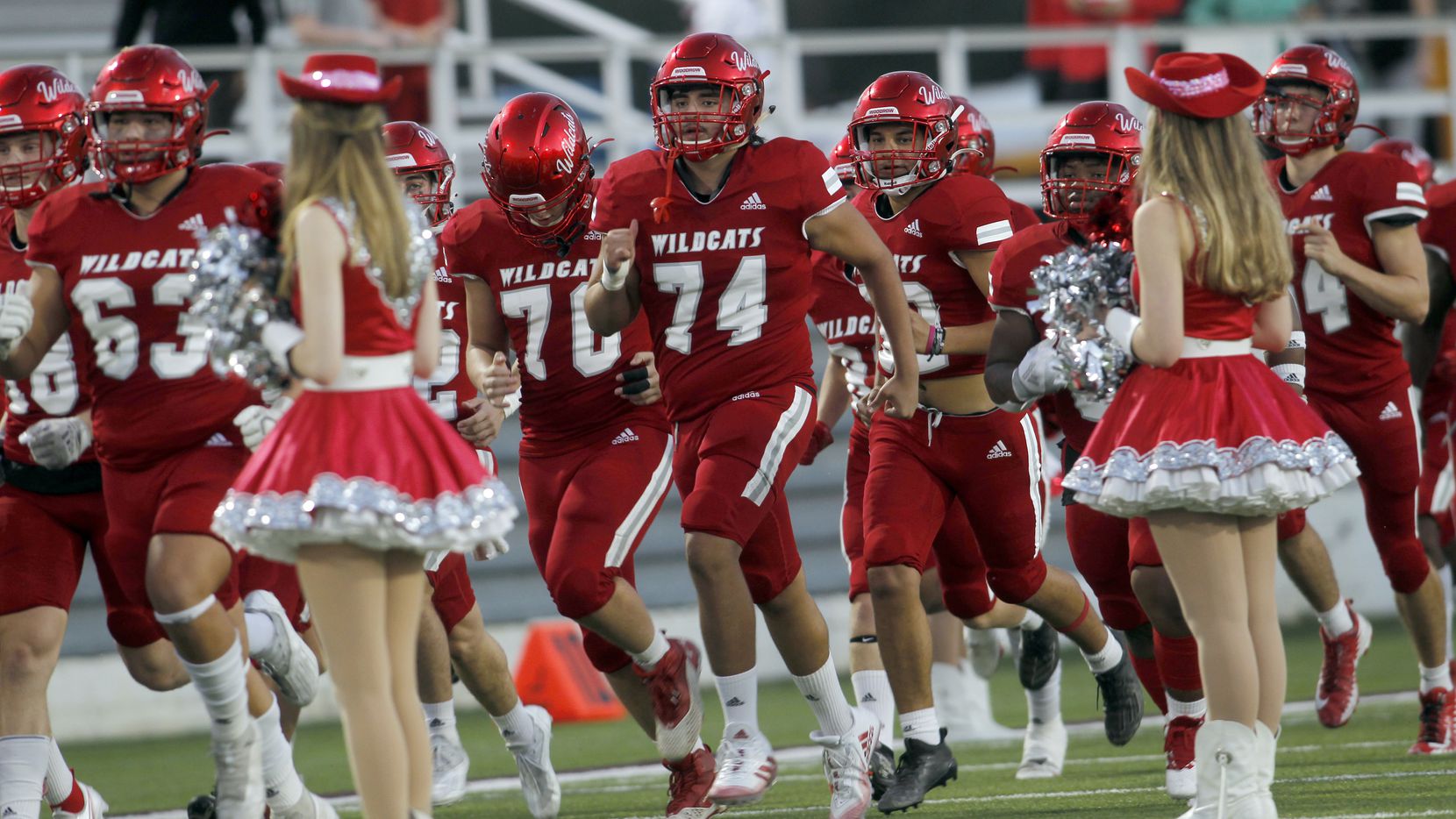 Members of the Dallas Woodrow Wilson Wildcats run onto the field before the opening kickoff...