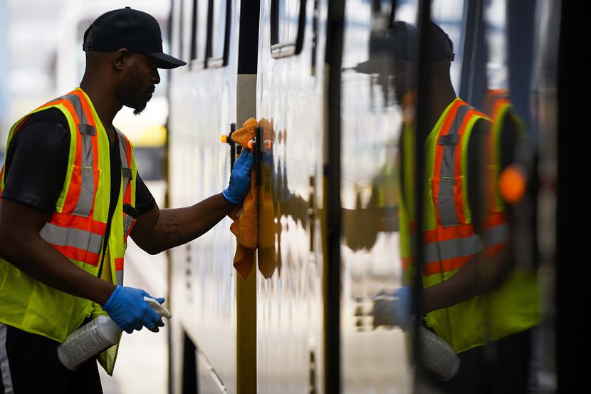 Michael Beck wipes down push buttons with disinfectant as he cleans a DART rail train at the...