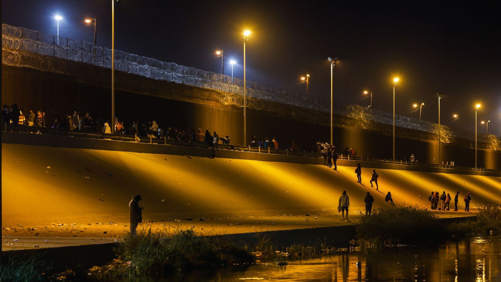 Migrants stand in line at a US-Mexico border gate from the banks of the Rio Grande River in...