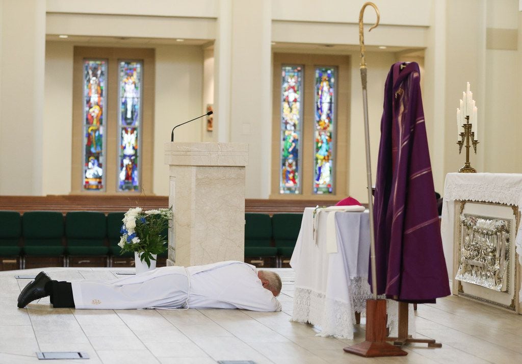 Bishop Edward J. Burns lies prostrate on the altar as a sign of humility and penance during...