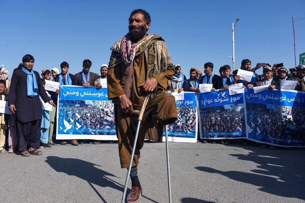 Afghan protesters march for peace and cease-fire as they hold banners in the Kandahar...