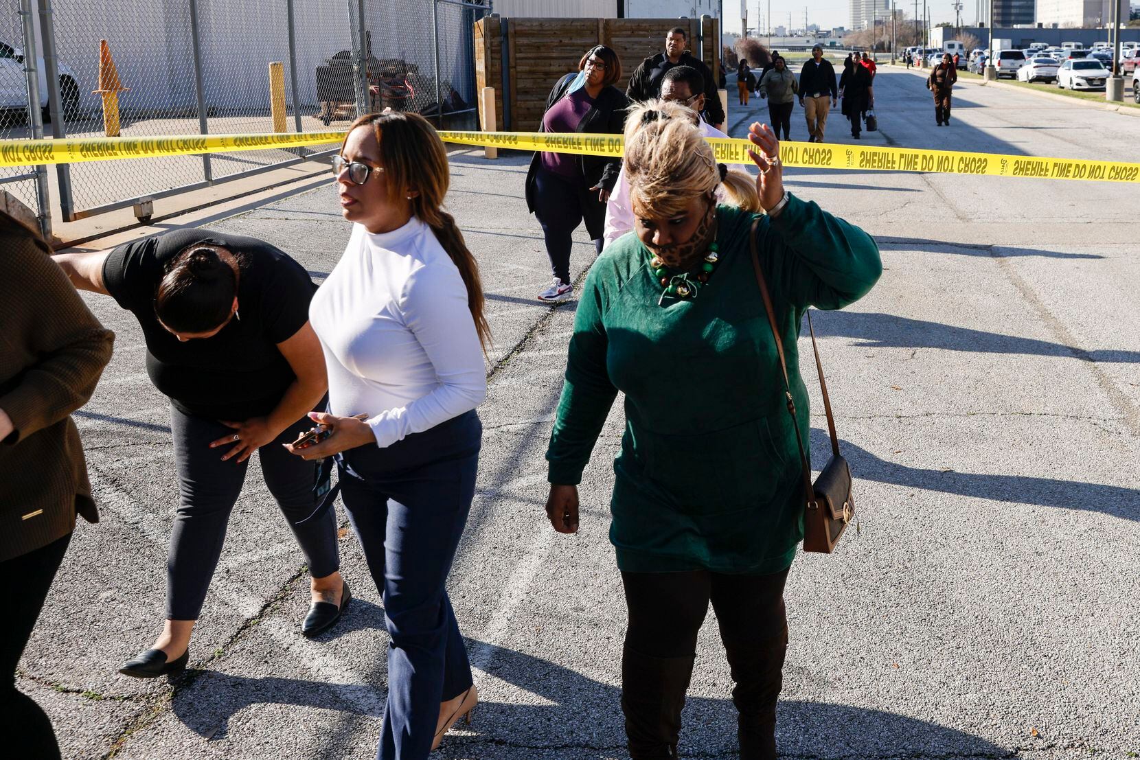 People cross under police tape after evacuating from the Dallas County Health and Human...