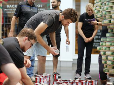 Ridgemont Construction's Zach Hanlon (center) places cans in the correct spot during the Canstruction charity event at NorthPark.