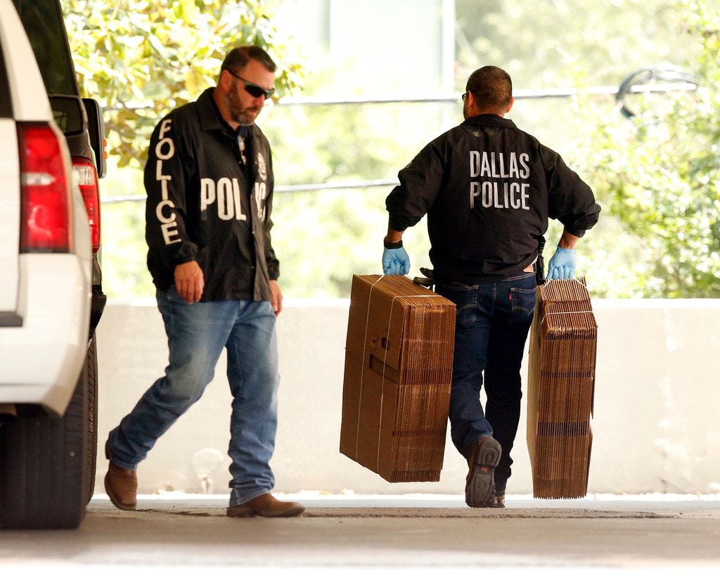 Dallas police officials carry cardboard boxes into the Catholic Diocese of Dallas as they...