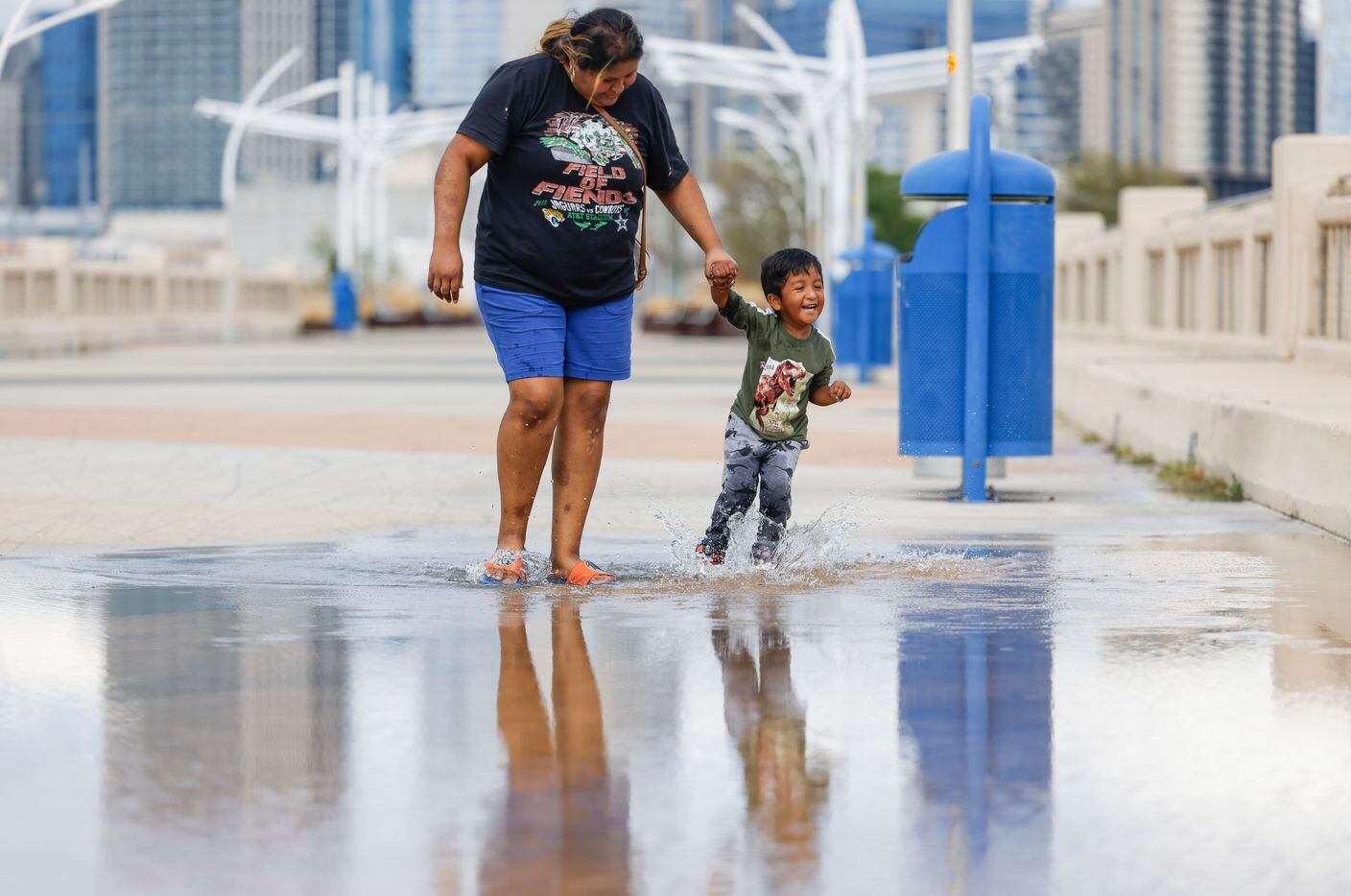 Christian Falgado, 3, right, jumps on stagnant storm water along Ronald Kirk Pedestrian...