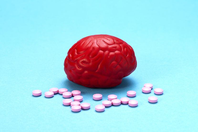 Red brain on a blue background with pink pills. Some pills for the brain. It is symbolic for...