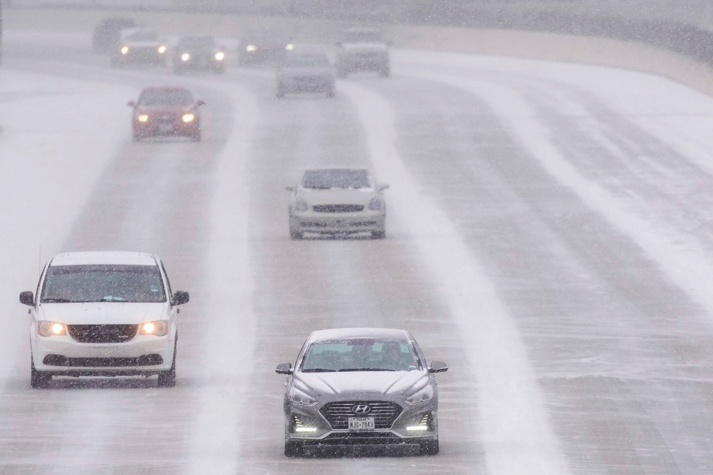 Traffic moves through snow on US-75 near the High Five interchange as a winter storm brings snow and freezing temperatures to North Texas on Sunday, Feb. 14, 2021, in Dallas.  A winter storm watch has been issued for all of North Texas, including Dallas, Denton, Collin and Tarrant counties and will be in effect from late Saturday through Monday afternoon. (Smiley N. Pool/The Dallas Morning News)