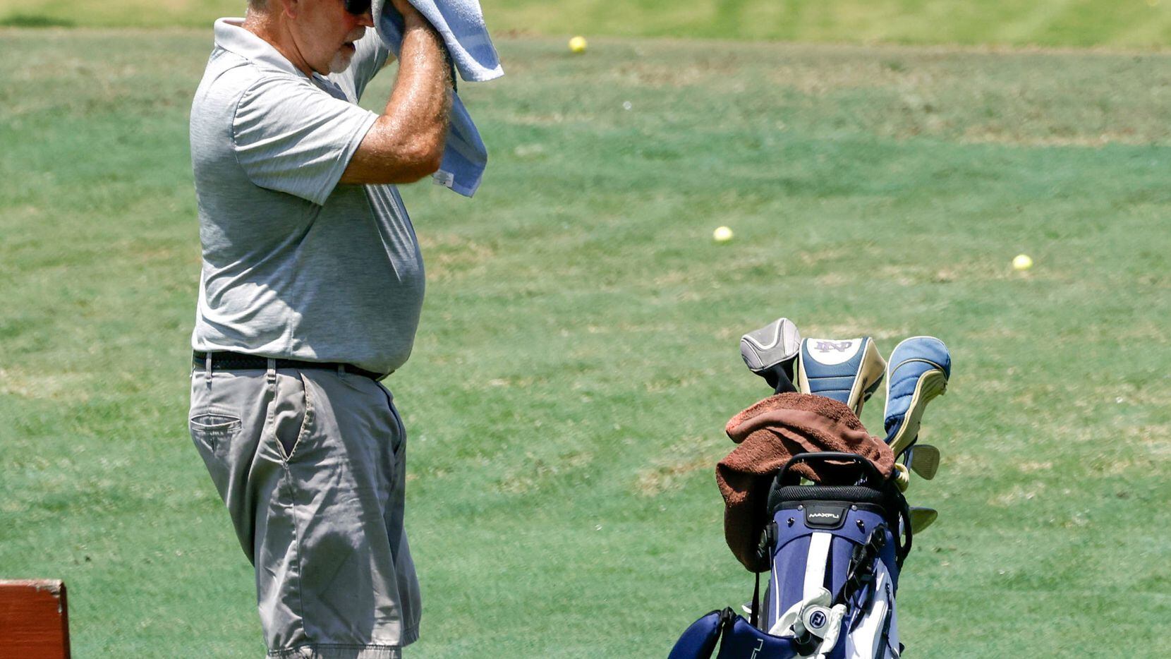 Larry McCrief uses a towel to wipe sweat from his face as he warms up for round of golf at...